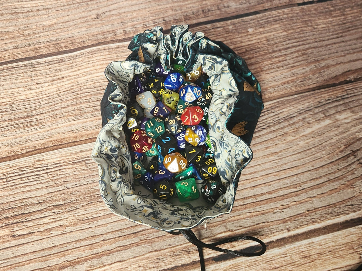 Open handmade dragon-scale drawstring dice bag filled with assorted polyhedral dice to demonstrate capacity; dice are shown for display and are not included.