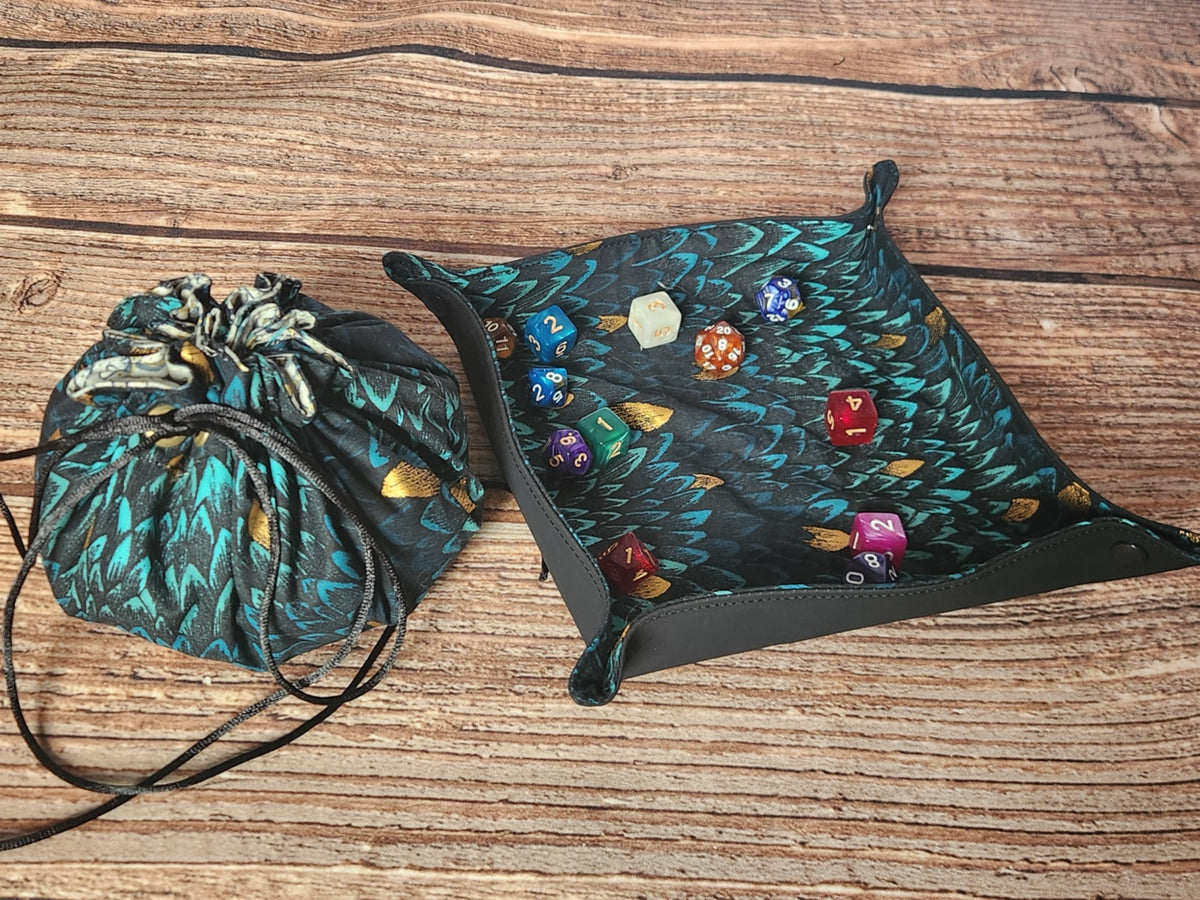 Handmade dragon-scale drawstring dice bag shown beside the matching snap-corner dice tray with assorted polyhedral dice; dice and dice tray are shown for styling and are not included with the bag.